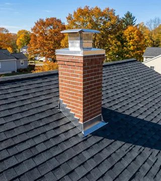 After: red brick chimney with a stainless cap and new step flashing on a fresh roof